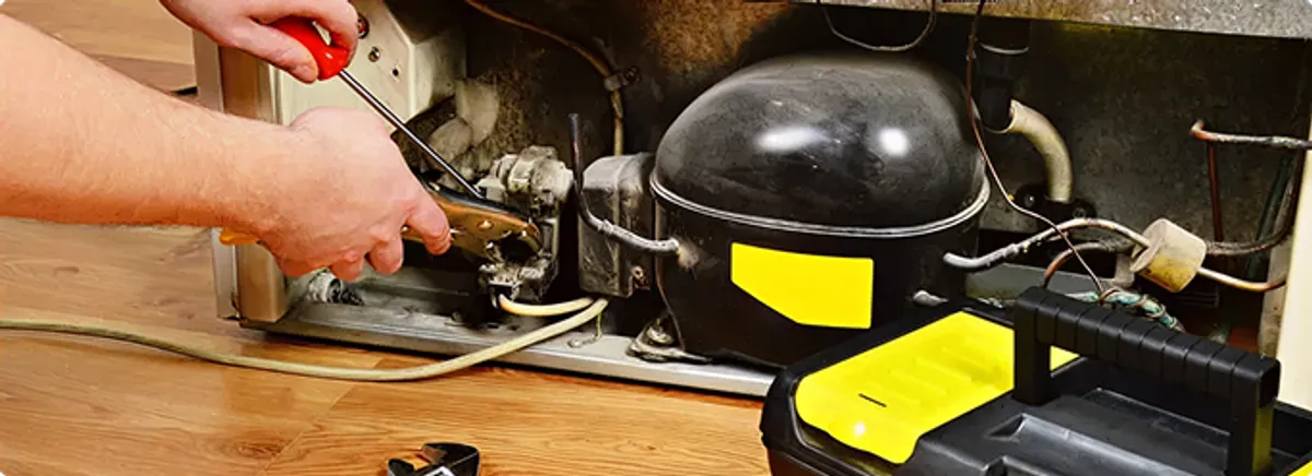 Refrigerator repair technician fixing the compressor and wiring in Hallandale, FL