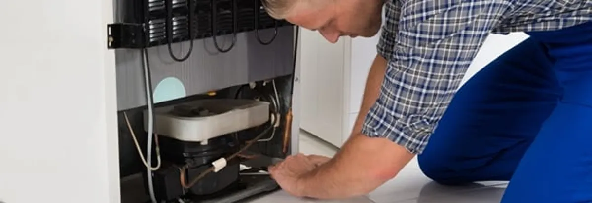 Refrigerator repair technician servicing the compressor and condenser area in Hialeah, FL