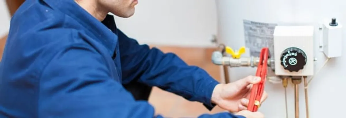 Water heater repair technician adjusting the temperature control and gas valve in Hialeah, FL